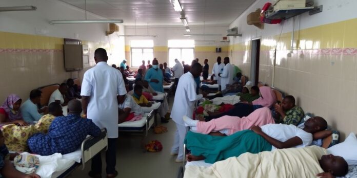 Crowded hospital ward in Abuja with patients and staff.
